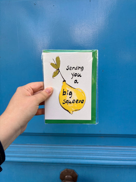 Hand holding a card with a lemon illustration and text against a blue background