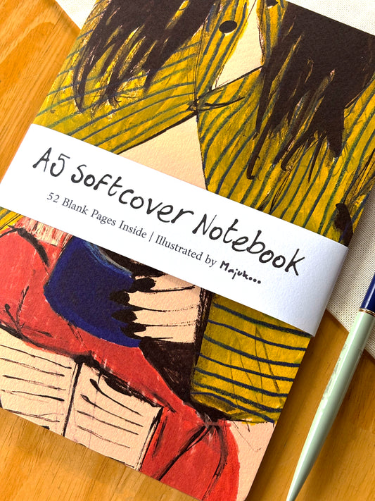 A5 softcover notebook with colorful illustration and 'Majukooo' branding on a wooden surface.