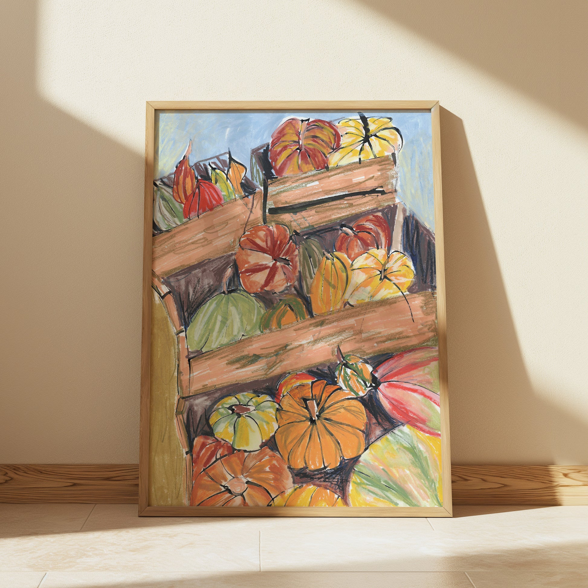 Framed painting of pumpkins on a wooden crate against a beige wall.