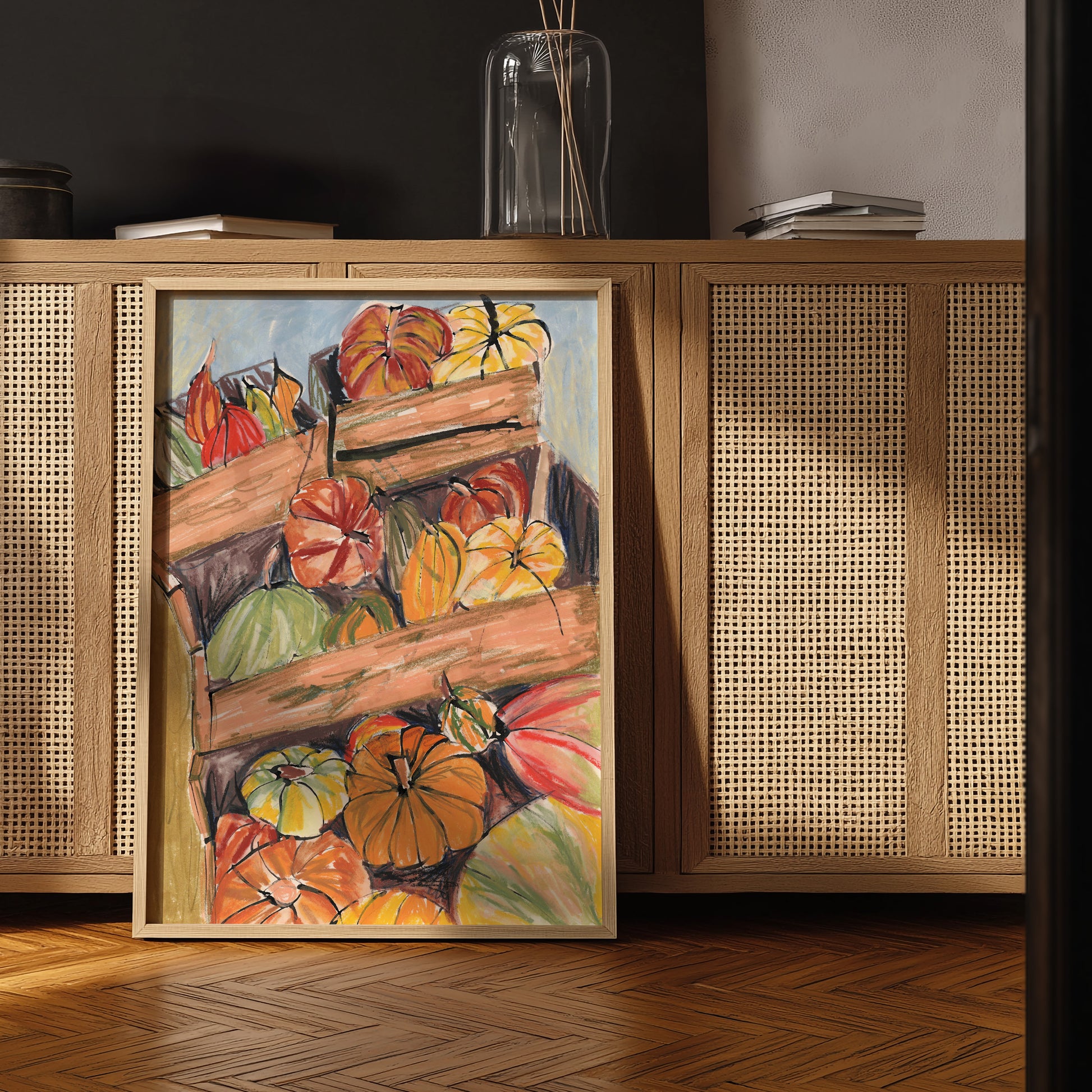 Framed painting of pumpkins on a wooden cabinet with rattan doors.