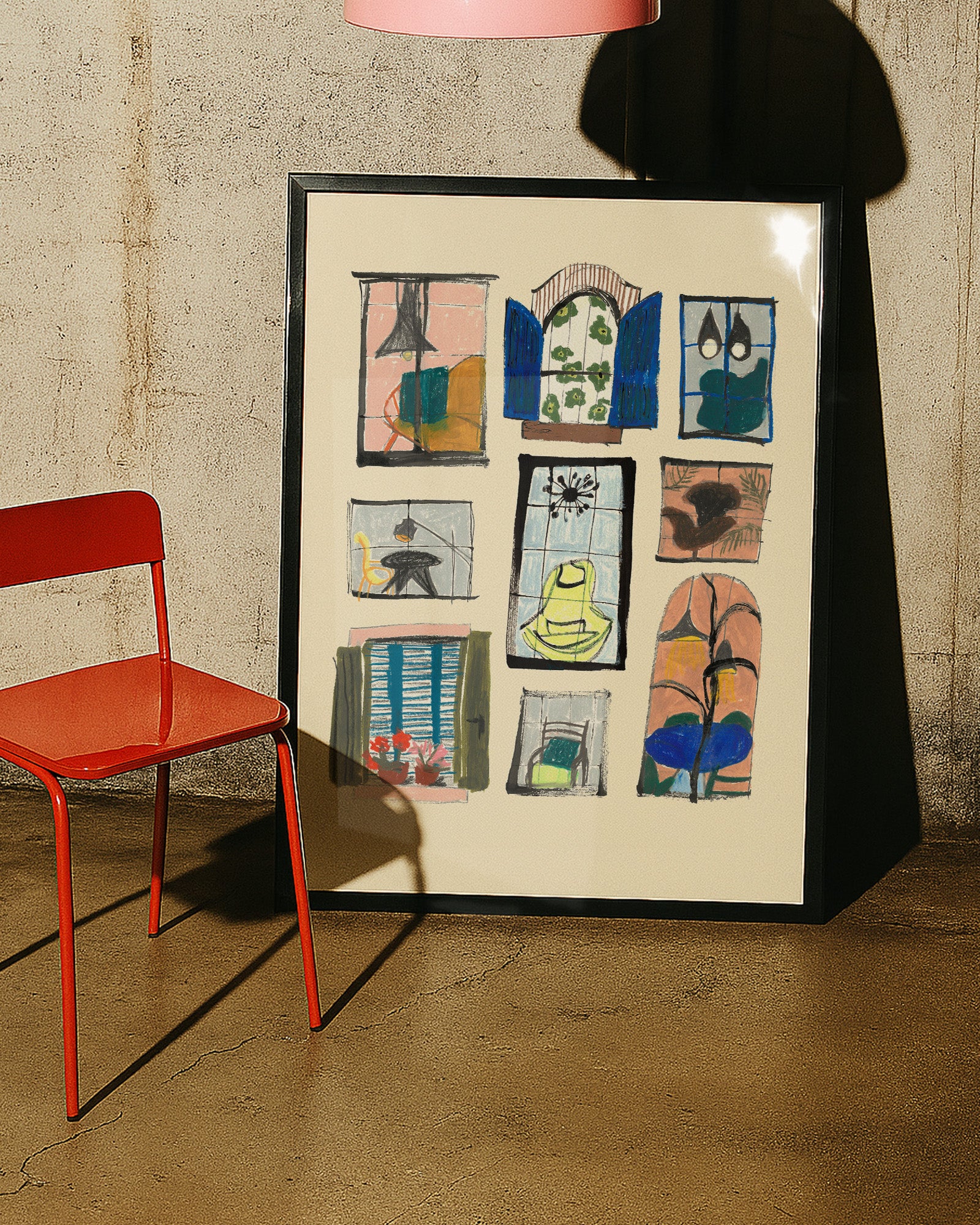 Framed artwork with colorful abstract designs next to a red chair against a textured wall.