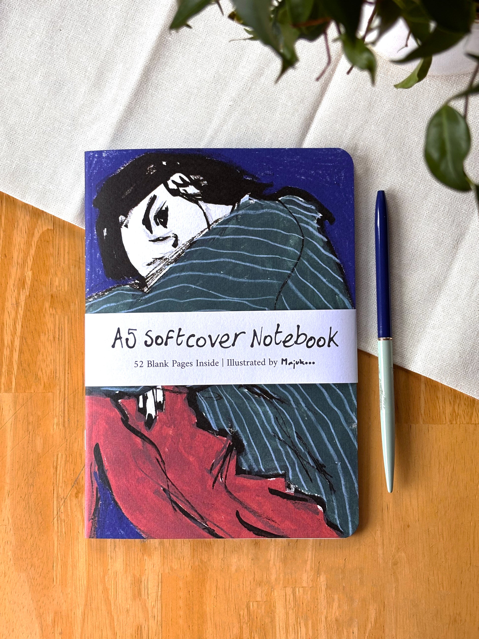 A5 Softcover Notebook with artistic cover design on a wooden surface