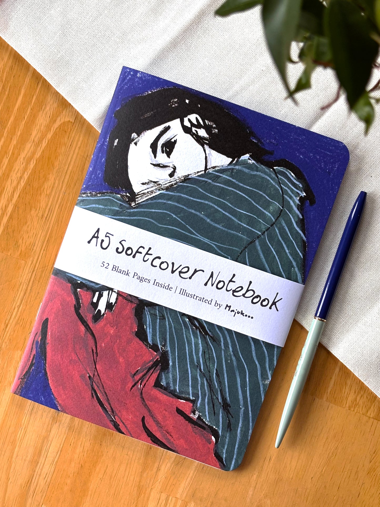 Notebook with artistic cover on a wooden surface with a pen