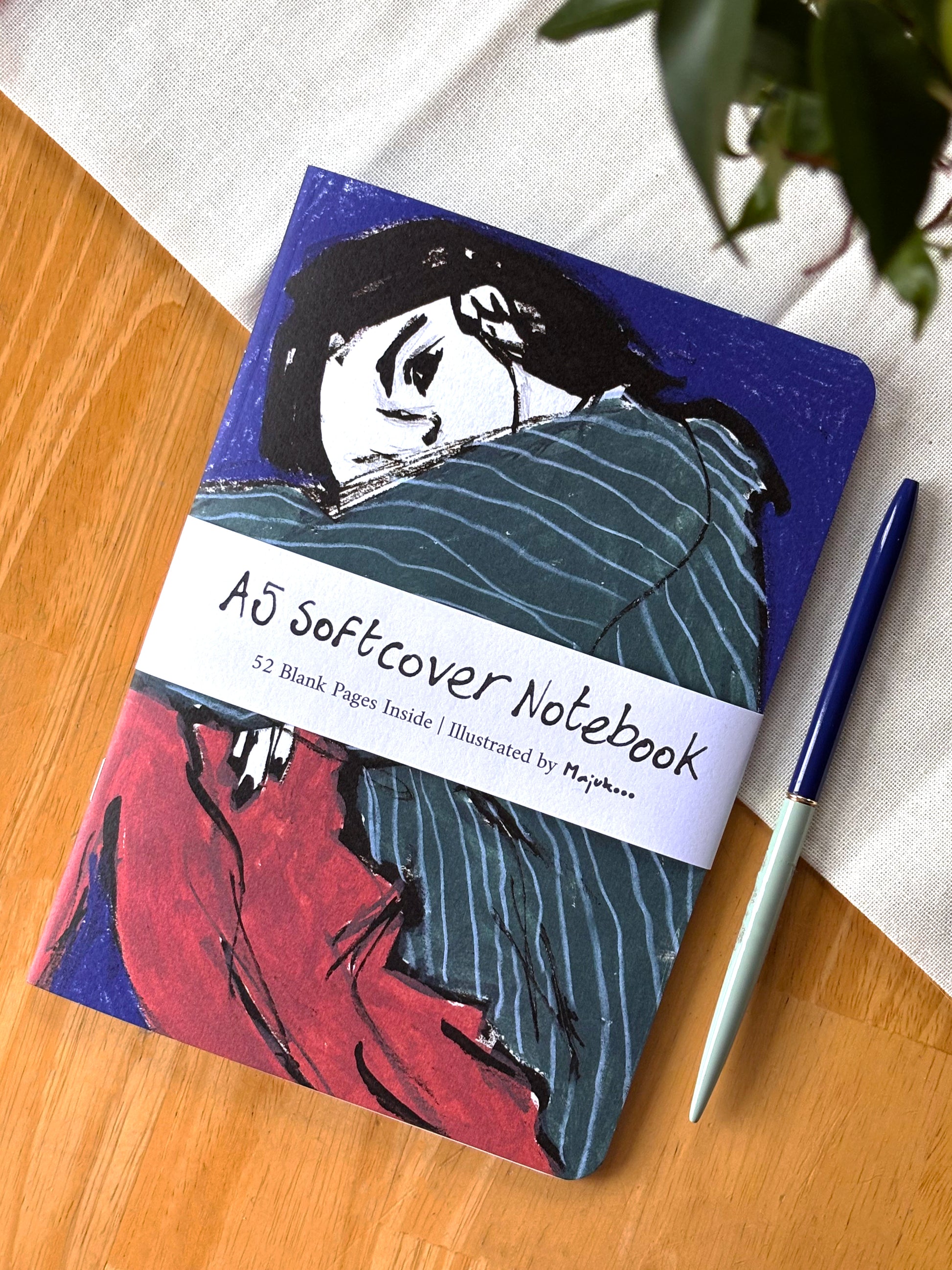 Notebook with artistic cover on a wooden surface with a pen