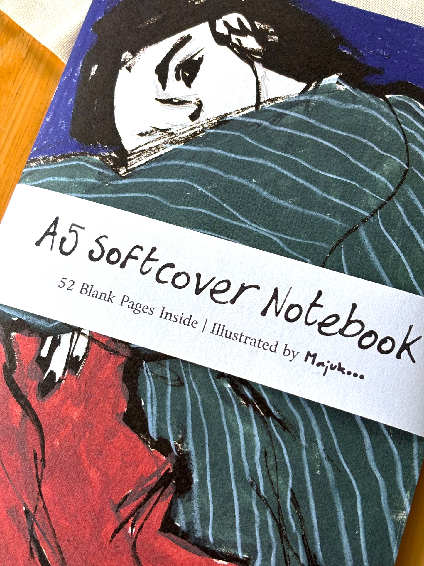 Notebook with artistic cover illustration and text about softcover size and blank pages.