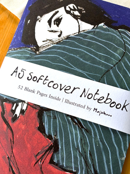 Notebook with artistic cover illustration and text about softcover size and blank pages.