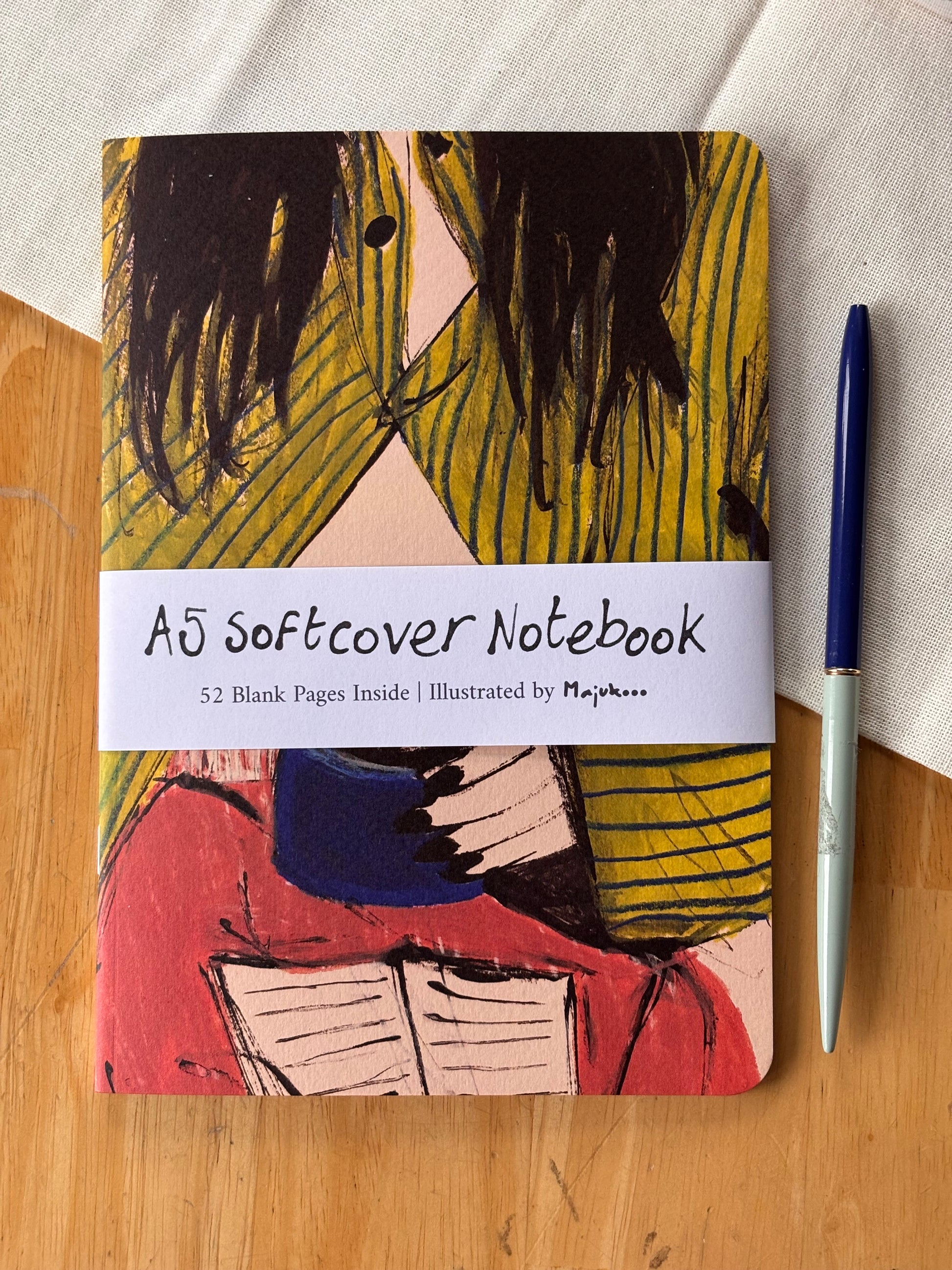 Notebook with abstract morning coffee design on cover and pen on wooden surface