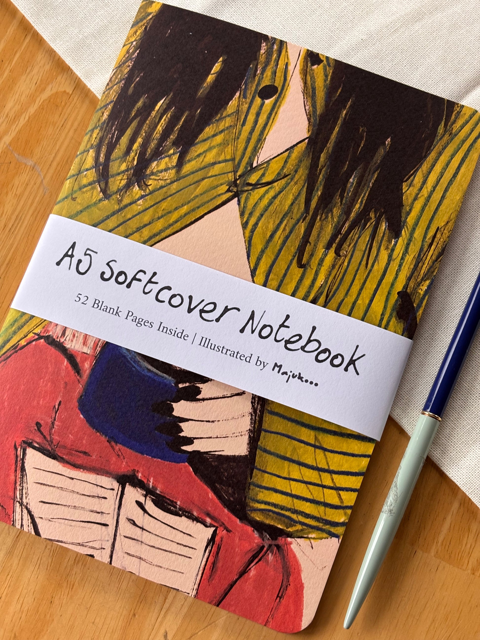 Notebook with abstract striped pyjama design and a pen on a wooden surface