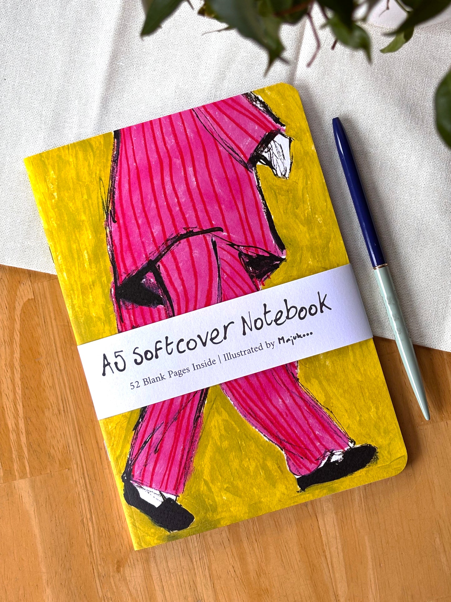 Notebook with a colorful pink striped pyjama cover on a wooden surface.