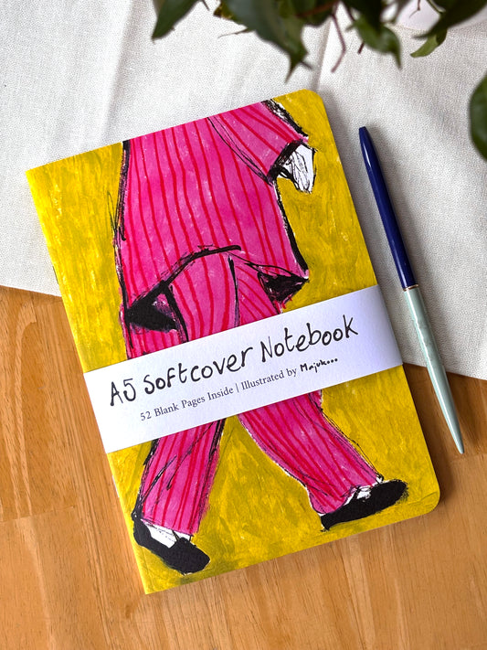 Notebook with a colorful pink striped pyjama cover on a wooden surface.